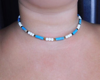 Könnte beinhalten: Eine blaue, weiße und goldene Perlenkette. Die Kette besteht aus kleinen, runden Perlen und rechteckigen Perlen.