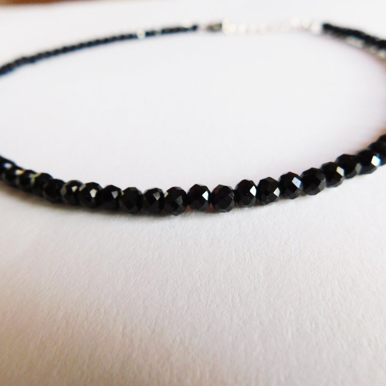 May include: A delicate black choker necklace made with small, faceted black onyx beads.