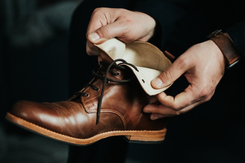 May include: A brown leather boot with a white leather lining. The boot is laced up and has a brown sole.