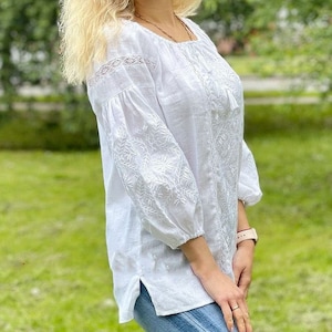 White on white vyshyvanka blouse with folk floral embroidery. Linen peasant blouse for women features puff sleeves that are decorated with ukrainian embroidery and lace. Linen top has 3/4 sleeves.