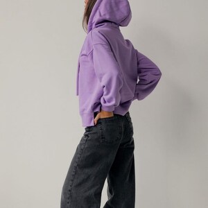 May include: A purple hooded sweatshirt with long sleeves and a relaxed fit. The sweatshirt is made of a soft, comfortable fabric.