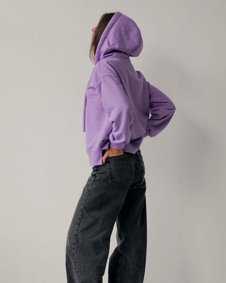 May include: A purple hooded sweatshirt with long sleeves and a relaxed fit. The sweatshirt is made of a soft, comfortable fabric.