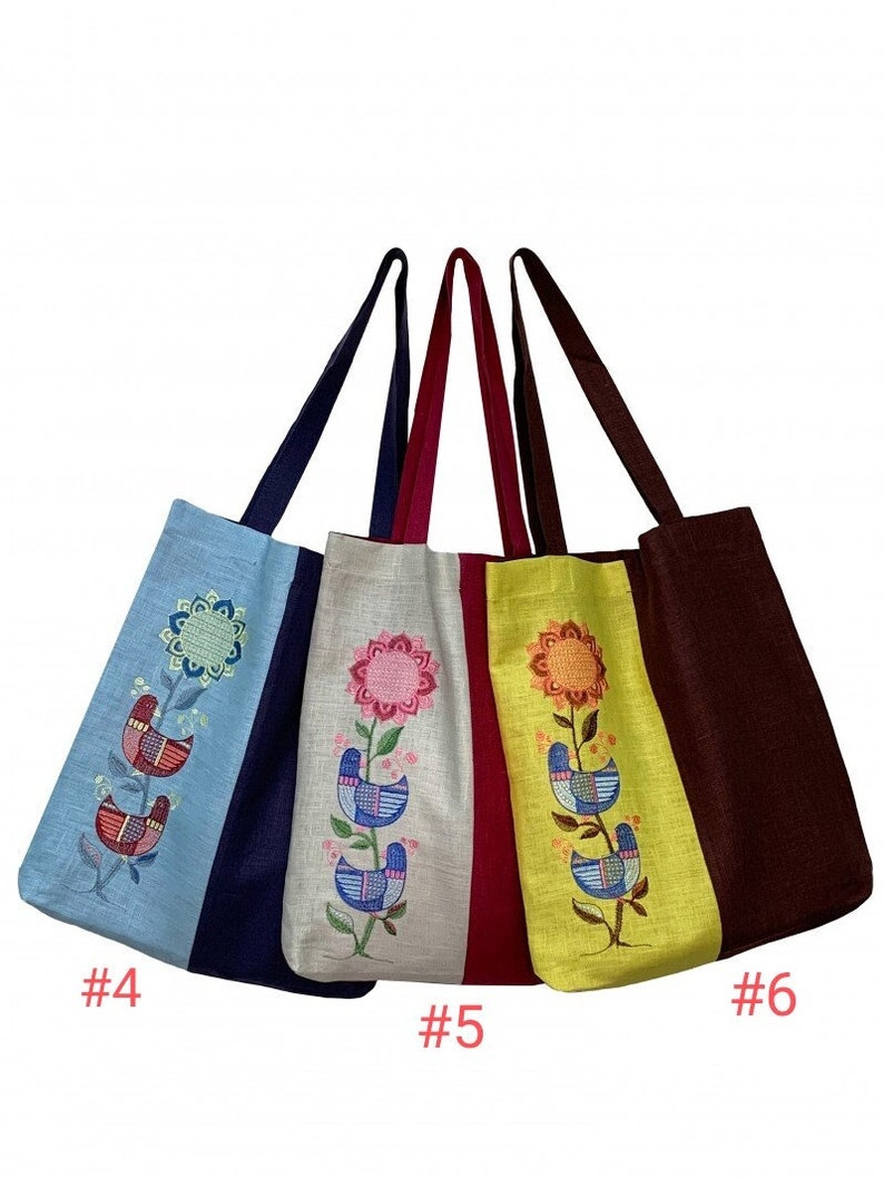 Puede incluir: Cuatro bolsos tote con dise&ntilde;os florales y de p&aacute;jaros bordados. Los bolsos son de varios colores, incluyendo azul claro, blanco roto, amarillo y marr&oacute;n. Cada bolso tiene un asa de diferente color y un patr&oacute;n bordado &uacute;nico.