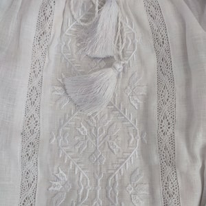 Peut inclure: Chemise en lin blanc avec broderie blanche et bordure en dentelle. La chemise a un lien &agrave; glands blanc au niveau du col.