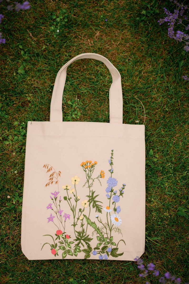 Beige canvas tote bag with botanical embroidery.