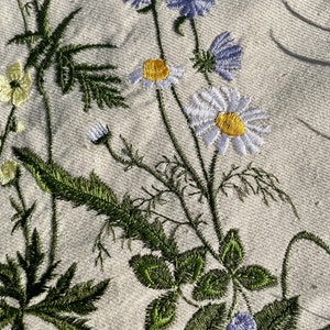 Beige canvas tote bag with botanical embroidery.