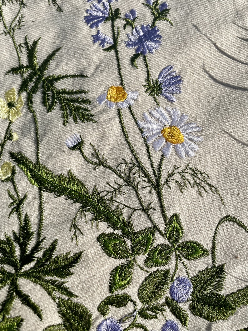 Beige canvas tote bag with botanical embroidery.
