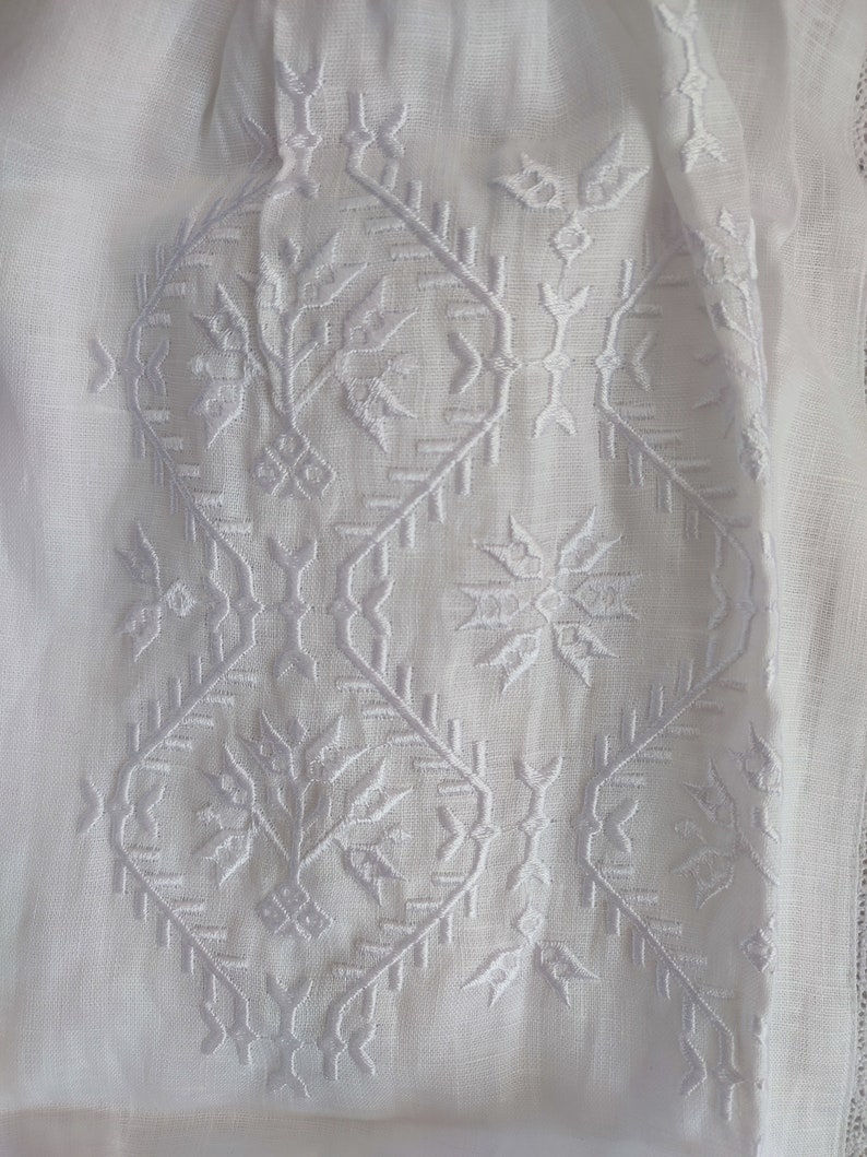 Peut inclure: Tissu de lin blanc avec un motif brod&eacute; blanc. Le motif pr&eacute;sente des formes g&eacute;om&eacute;triques et des motifs.