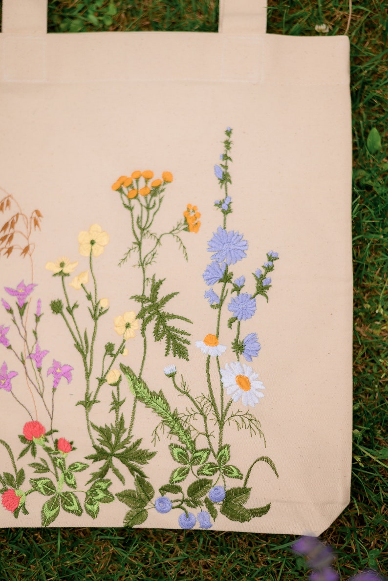 Beige canvas tote bag with botanical embroidery.