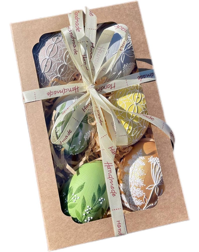 Set of 6 hand-painted Easter eggs in soft pastel green, grey, yellow and beige tones with white botanical line art, gold details and pearl dots