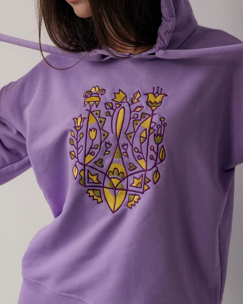 May include: A purple hoodie with a yellow and green embroidered design of stylized flowers and leaves.