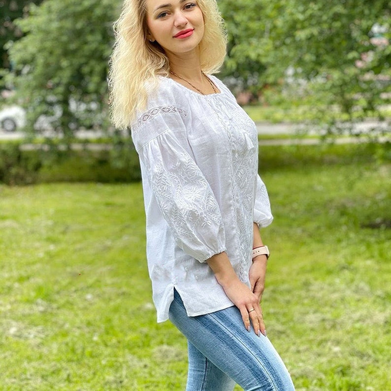 White on white vyshyvanka blouse with folk floral embroidery. Linen peasant blouse for women features puff sleeves that are decorated with ukrainian embroidery and lace. Linen top has 3/4 sleeves.