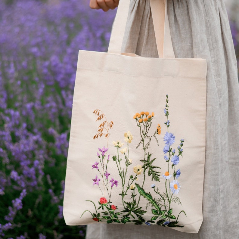 Beige canvas tote bag with botanical embroidery.