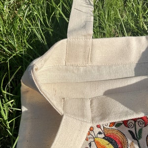 Beige canvas tote bag with folk floral embroidery.