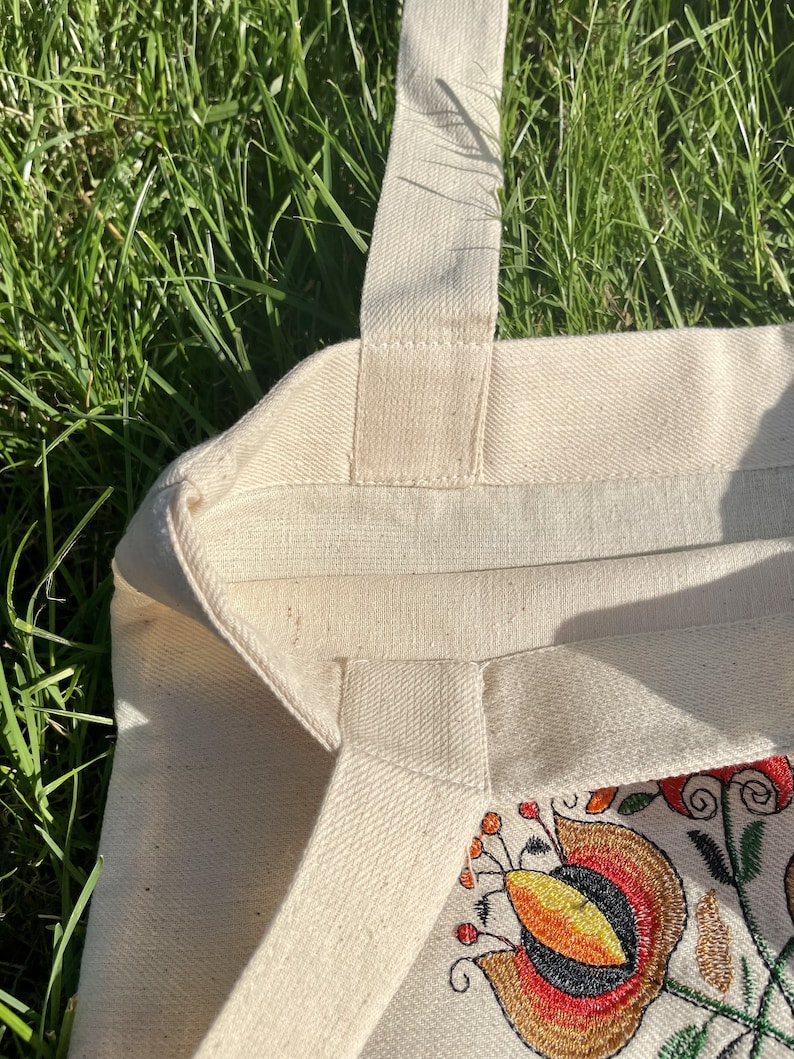 Beige canvas tote bag with folk floral embroidery.