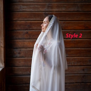 Puede incluir: Un velo blanco con un ribete decorativo y un vestido blanco a juego. El velo est&aacute; drapeado sobre la cabeza y los hombros. El texto "Style 2" es visible en la imagen.