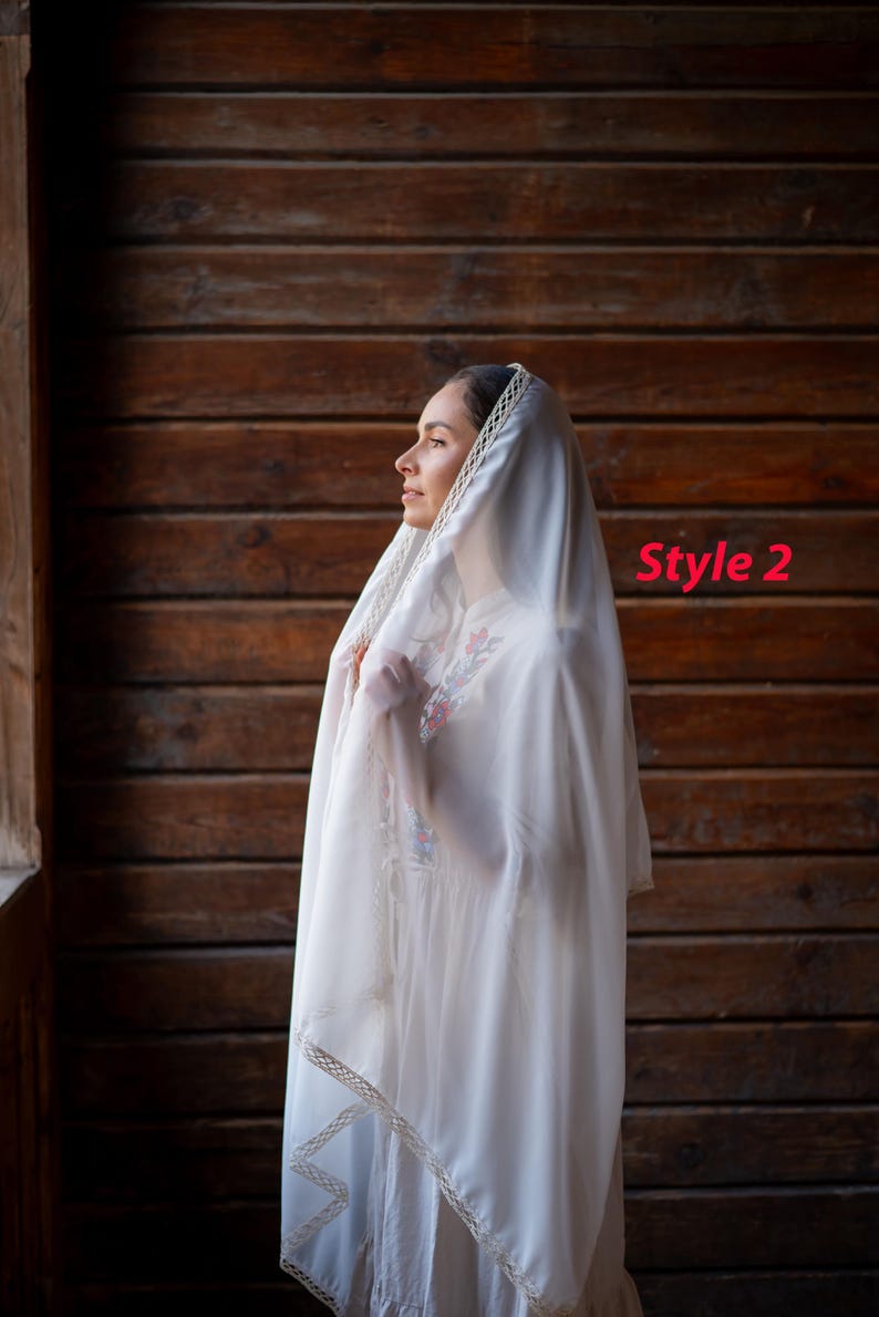 Puede incluir: Un velo blanco con un ribete decorativo y un vestido blanco a juego. El velo est&aacute; drapeado sobre la cabeza y los hombros. El texto "Style 2" es visible en la imagen.