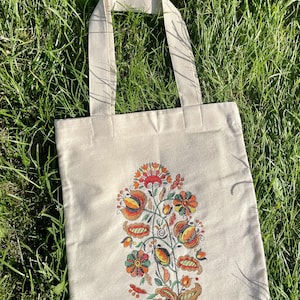 Beige canvas tote bag with folk floral embroidery.