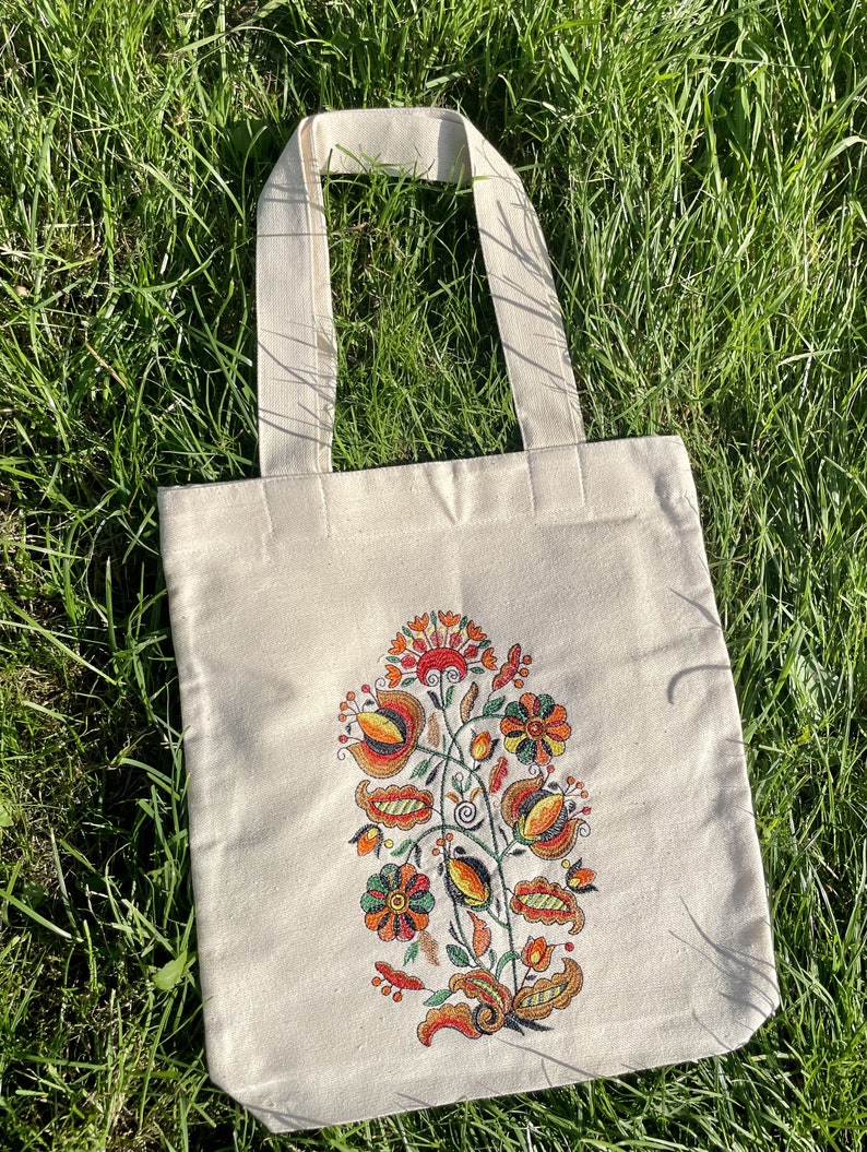 Beige canvas tote bag with folk floral embroidery.