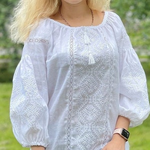 White on white vyshyvanka blouse with folk floral embroidery. Linen peasant blouse for women features puff sleeves that are decorated with ukrainian embroidery and lace. Linen top has 3/4 sleeves.
