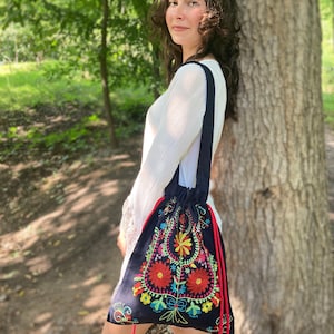 May include: A dark blue drawstring bag with colorful floral embroidery. The bag has red tassels.
