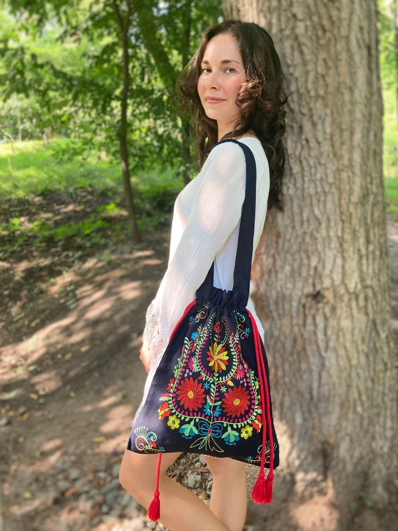 May include: A dark blue drawstring bag with colorful floral embroidery. The bag has red tassels.