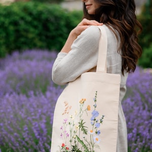 Beige canvas tote bag with botanical embroidery.