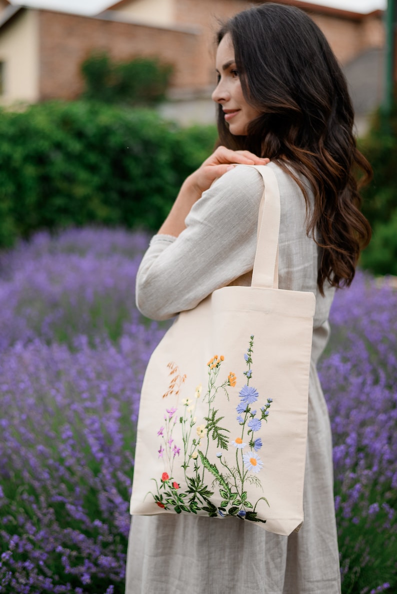 Beige canvas tote bag with botanical embroidery.