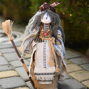 Può includere: Bambola fatta a mano raffigurante una strega con una scopa. La bambola ha lunghi capelli grigi, una testa di stoffa ed è vestita con un abito dettagliato e fantasia con una cintura di corda. Un oggetto decorativo unico.