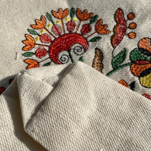 Beige canvas tote bag with folk floral embroidery.