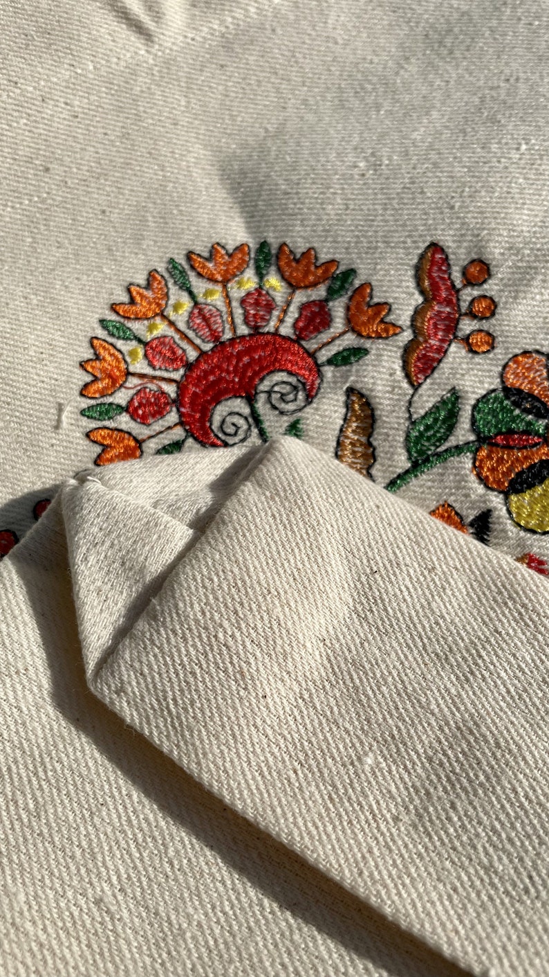 Beige canvas tote bag with folk floral embroidery.