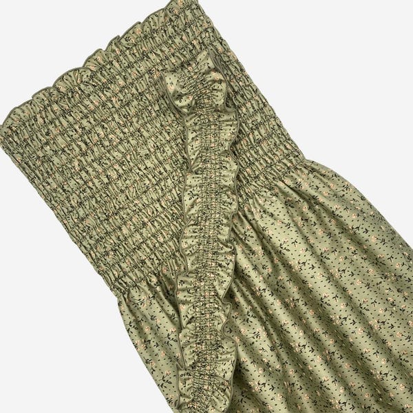 May include: A green floral print dress with a smocked bodice and a ruffled trim. The dress has a fitted bodice and a flowy skirt.