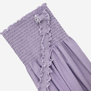 May include: A purple and white gingham strapless dress with a ruffled trim. The dress has a smocked bodice and a flowing skirt.