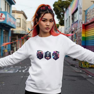 May include: White sweatshirt featuring three colorful alien-themed graphic designs. The graphics are in a row and are framed in a shield shape. The sweatshirt is a crew neck style and has long sleeves.