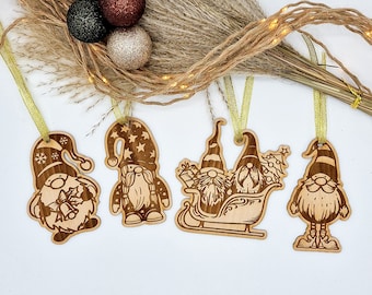 May include: Four wooden ornaments featuring gnomes in various poses. One gnome is riding in a sleigh pulled by another gnome. Another gnome is holding a gift. The ornaments are painted in shades of brown and have a rustic look.