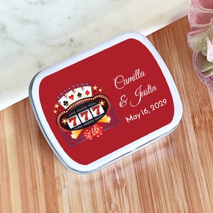 May include: Red and white rectangular tin with a slot machine graphic and playing cards. The text reads "Camilla & Justin May 16, 2029".