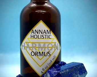 Könnte beinhalten: Eine braune Glasflasche mit schwarzem Deckel und einem gelb-weißen Etikett mit der Aufschrift "Annam Holistic Harmony Ormus 118 ml". Ein blaues Perlenarmband und ein blauer Kristall befinden sich vor der Flasche.