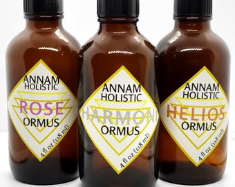 May include: Three amber glass bottles with black caps, each labeled with "Annam Holistic Ormus." The labels feature a diamond design with the words "Rose," "Harmony," and "Helios." Each bottle contains 4 fl oz (118 ml).