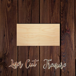 May include: A blank, rectangular piece of wood with a smooth, light brown surface. The wood is sitting on a dark brown wooden background.