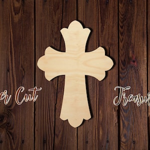 May include: A wooden cross with a decorative design, laser cut from wood. The cross is light brown and has a smooth finish. The cross is on a dark brown wooden background.
