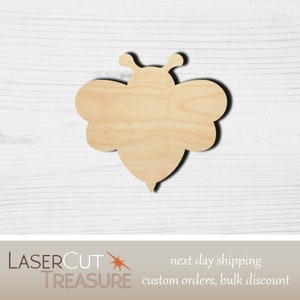 May include: Wooden cutout of a bee in a natural wood color. The bee has a rounded body and two small antennae.