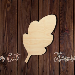 May include: A laser cut wooden leaf shape, with a natural wood color, against a dark brown wood background. The text "Laser Cut Treasure" is visible in the image.