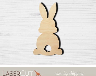 May include: A wooden cutout of a bunny rabbit in a sitting position. The bunny has a hole in the back, suggesting it is a craft project.