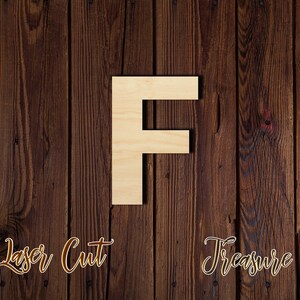 May include: A wooden letter F, laser cut and painted in a light brown color, against a dark brown wood background. The words "Laser Cut" and "Treasure" are written in cursive at the bottom of the image.