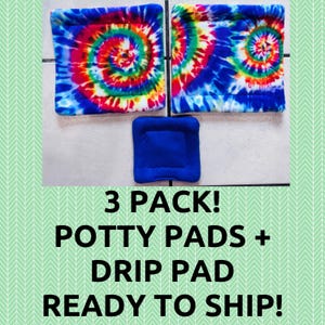 May include: A set of three square fabric pads. Two pads feature a vibrant multi-colored tie-dye spiral pattern in red, yellow, green, and blue. The third, smaller pad is solid royal blue. All items have a soft, plush texture and stitched edges.