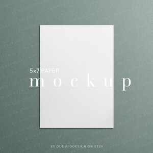 May include: A white 5x7 inch paper mockup against a textured teal background. The word "mockup" is displayed in a minimalist font. The text "5x7 PAPER" is above the word "mockup". The Etsy shop name "BY DODUFODESIGN ON ETSY" is at the bottom.