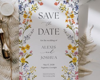 Peut inclure: Une invitation de mariage avec le texte "SAVE THE DATE" en écriture élégante. La carte est ornée d'une bordure florale colorée avec des fleurs jaunes, bleues et roses. Les noms Alexis et Joshua sont présentés, ainsi que la date et le lieu du mariage.