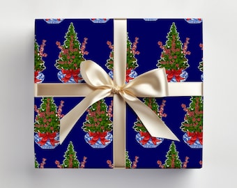 May include: A wrapped gift with navy blue wrapping paper featuring a repeating pattern of green Christmas trees in blue and white vases with red bows. The gift is tied with a cream-colored satin ribbon and bow.