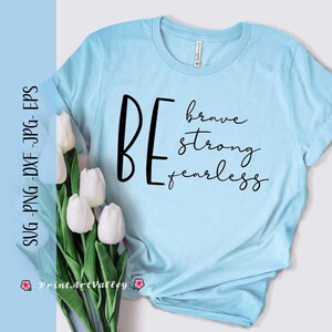 May include: A light blue t-shirt with the text "BE brave strong fearless" in black lettering.