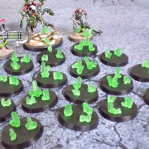 May include: A set of 18 green crystal gaming bases for miniature figures. Each base is a round black plastic disc with a cluster of green crystal-like pieces on top.